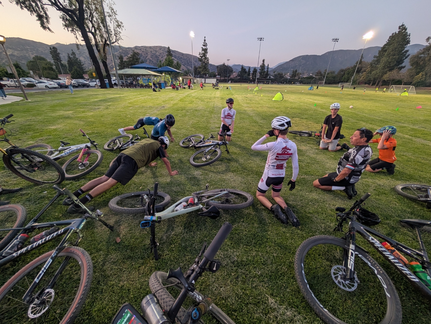 Wolfpack riders stretching in a circle at dusk practice with the San Gabriel mountains behind